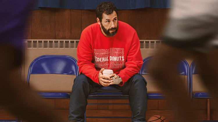 Adam Sandler in Hustle, observing basketball with a coffee in his hands