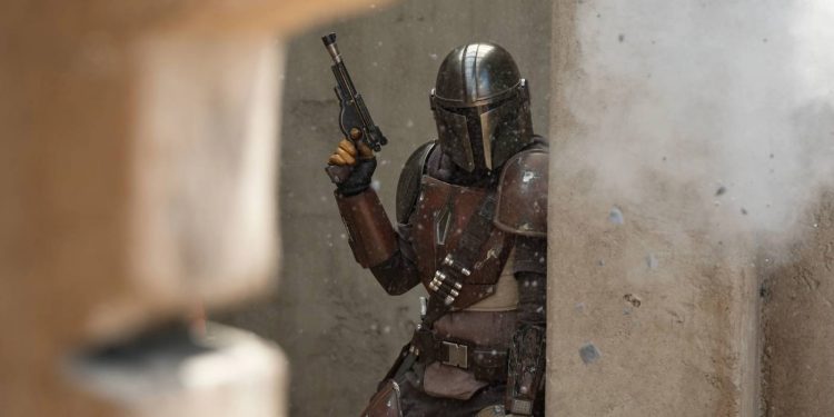 Din Djarin, The Mandalorian, holding his blaster at the ready.