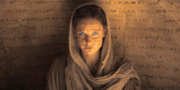 woman wearing desert garb with ancient text projected on her face