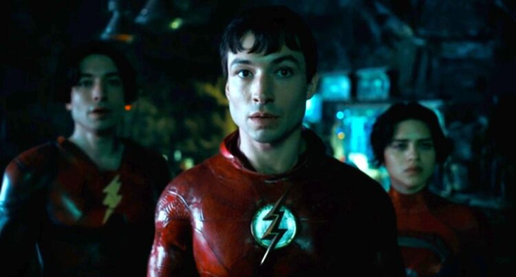 The Flash Ezra Miller as Barry Allen with alternate timeline Barry and Supergirl standing behind him.