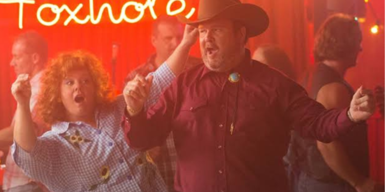 Eric Stonestreet and Melissa McCathy dancing in a room.