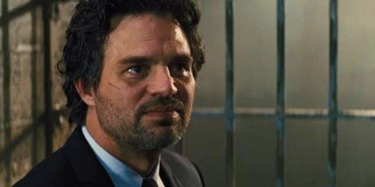 Mark Ruffalo in a suit and tie in a jail cell.