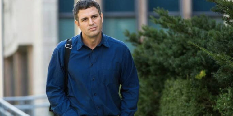 Mark Ruffalo in a blue shirt standing on a sidewalk