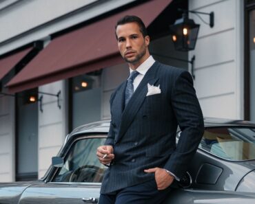 Tristan Tate poses for a photo in front of a car