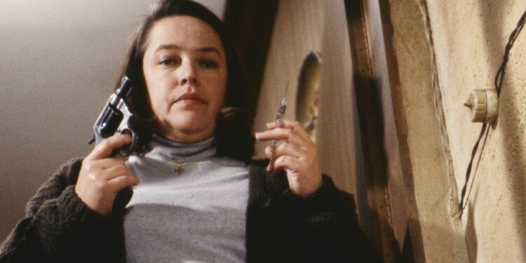 Annie Wilkes holding a gun and syringe