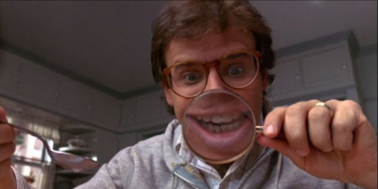 Rick Moranis holding a magnifier glass